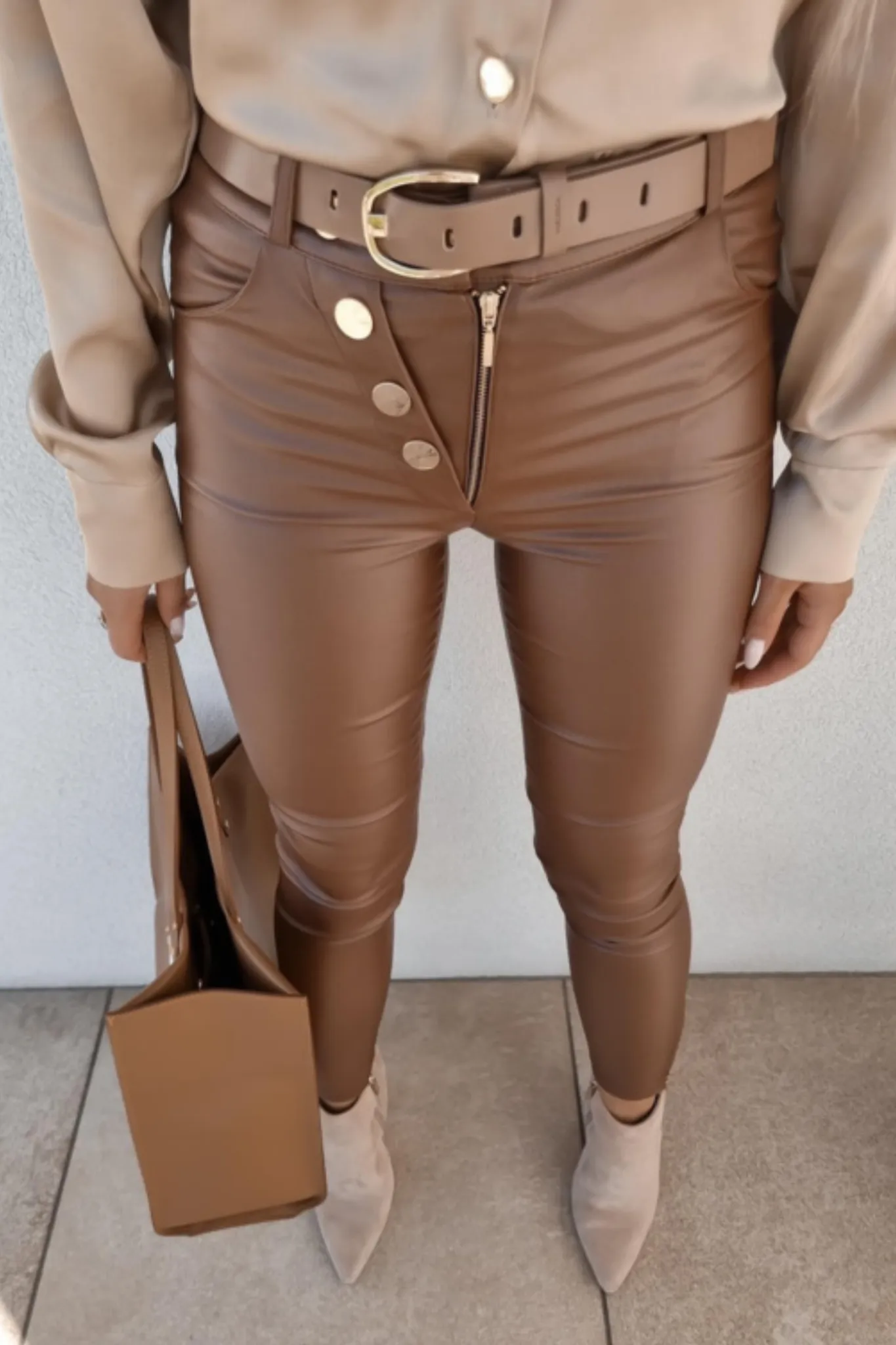 Pantaloni marrone bronzo in similpelle a vita alta accessoriati con bottoni e cerniere